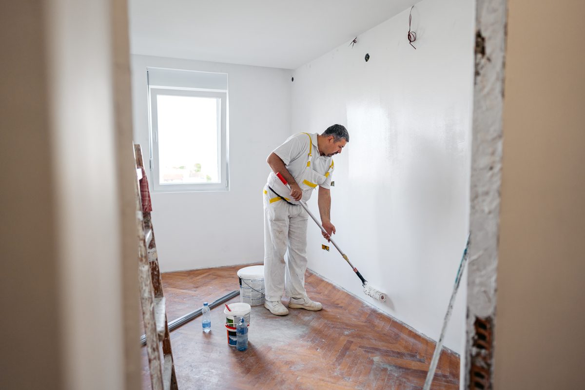 Decorator painting the walls of a refurbished room