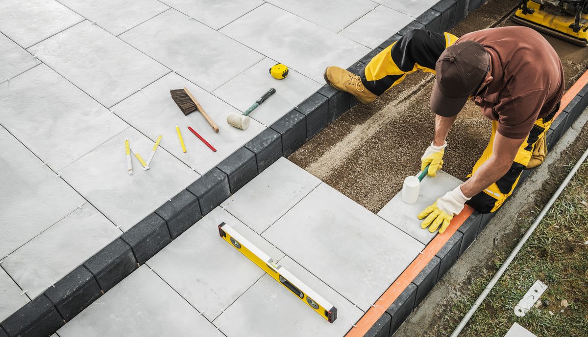 Tiler laying floor tiles using a spirit level