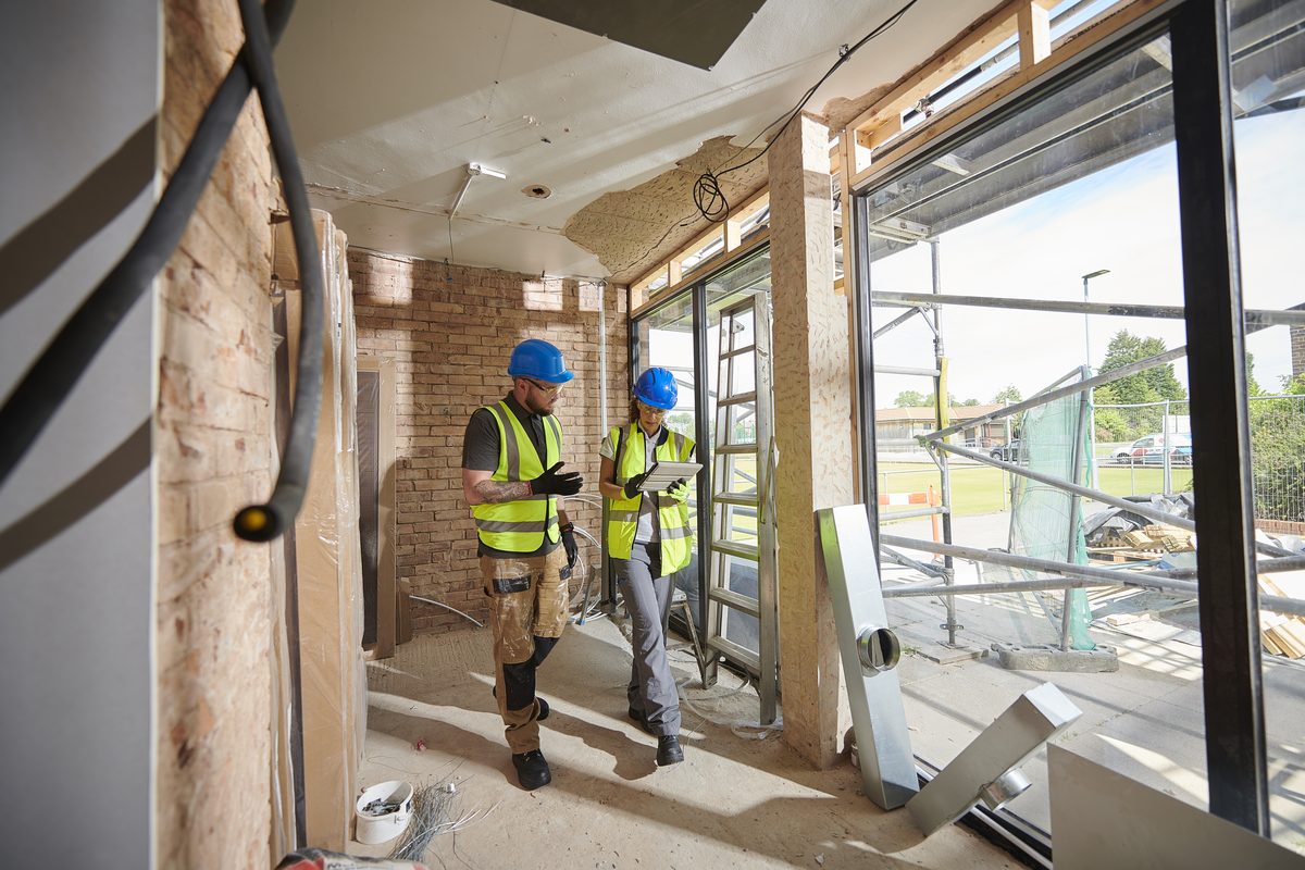 Worker in hi-vis installing a window during a refurbishment